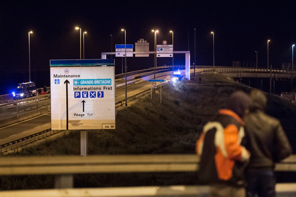 Fransk kravallpolis jagar bort migranterna som försöker ta sig upp på lastbilar som åker genom tunneln mot England.